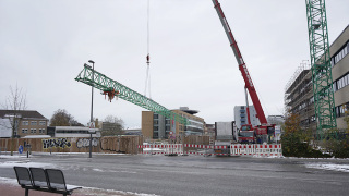 Ein Autokran demontiert den Kran am Laborneubau und verlädt die Einzelteile auf einen Tieflader.